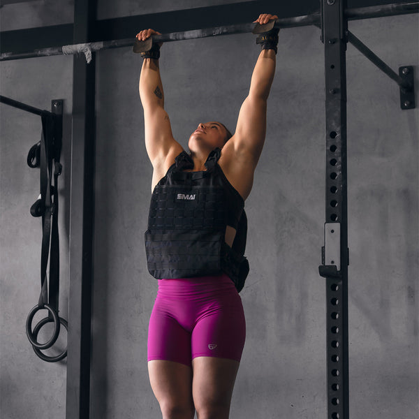 Woman hanging from pull up bar with a SMAI weight vest adjustable